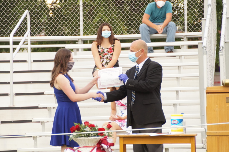 8th Grade Student receiving certificate of promotion from board president