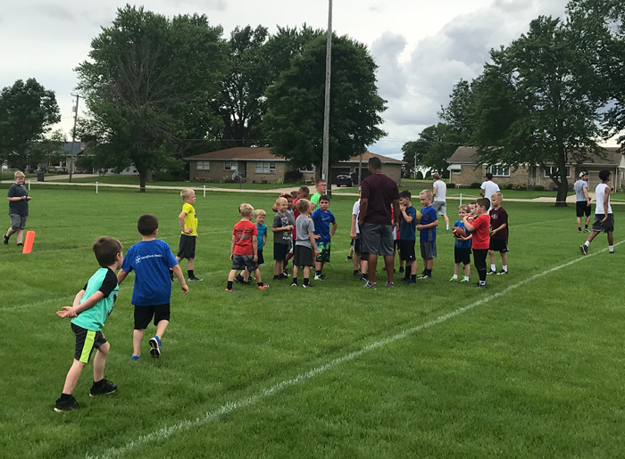 boys huddled around on football field listening to coach